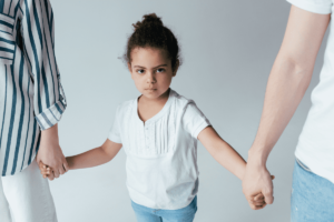 Child standing between two parents, each holding one of the child's hands